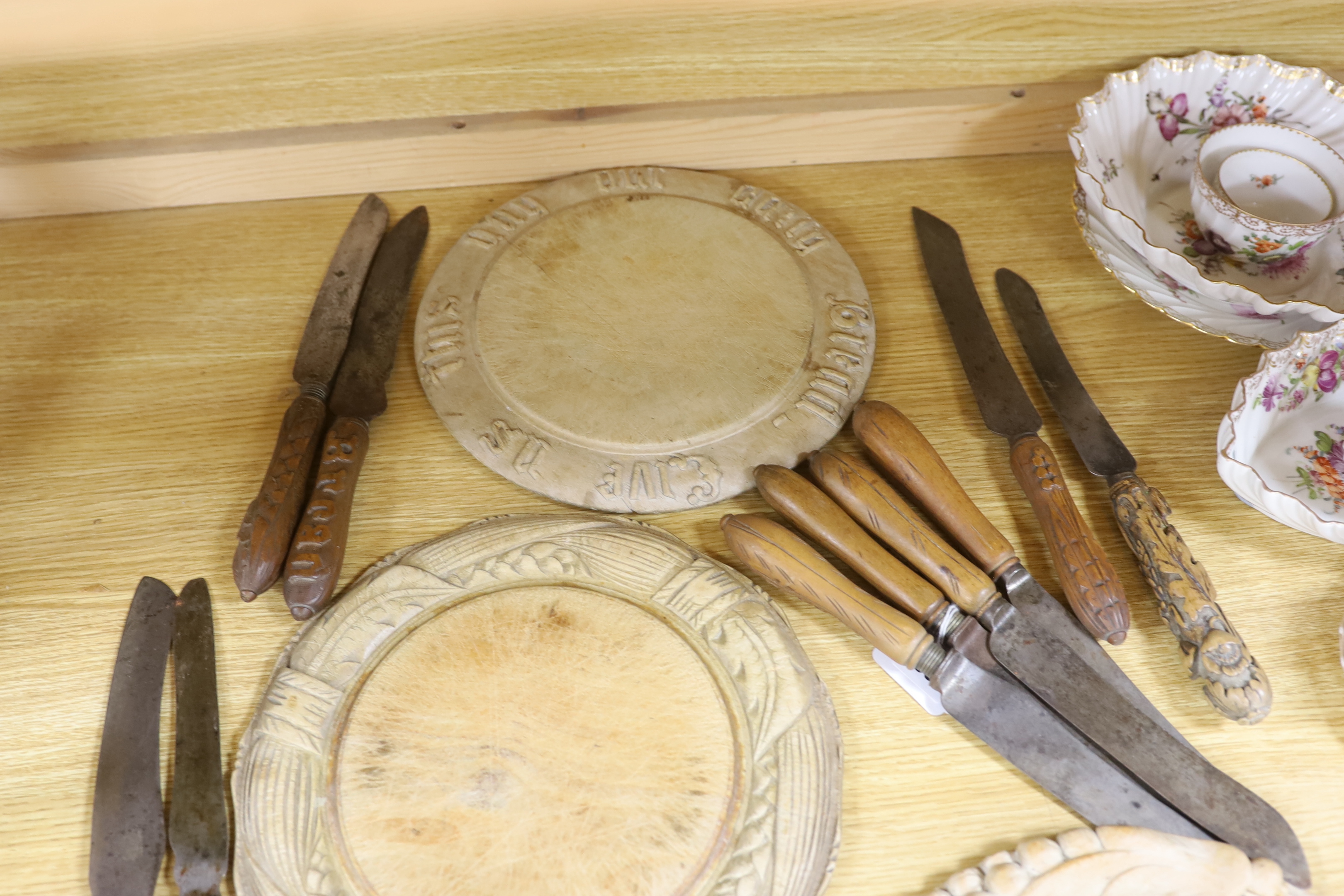 Three carved wood breadboards, a butter dish and a collection of knives with carved handles, largest 29cm in diameter